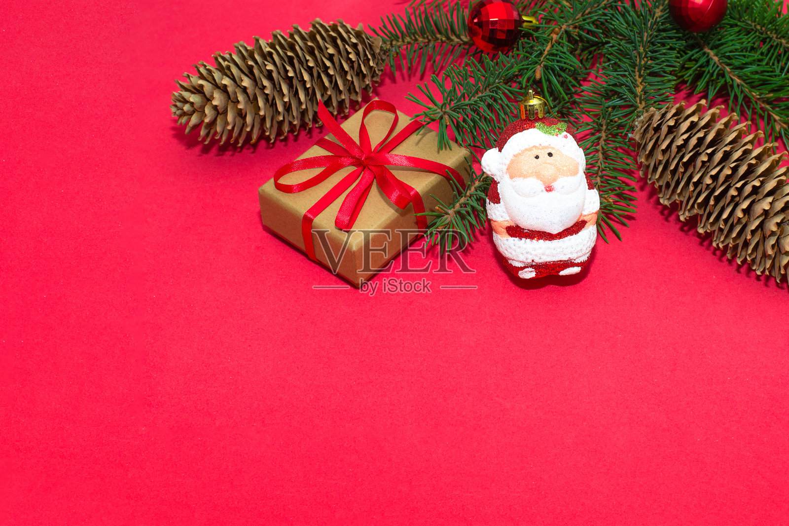 红色背景上有圆锥体和圣诞装饰的圣诞树树枝。一个极简主义的构图，庆祝的概念。照片摄影图片