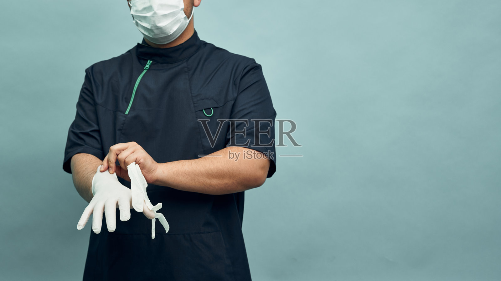 一位身着职业装的医生脱下防护手套。预防病毒的个人防护装备。照片摄影图片