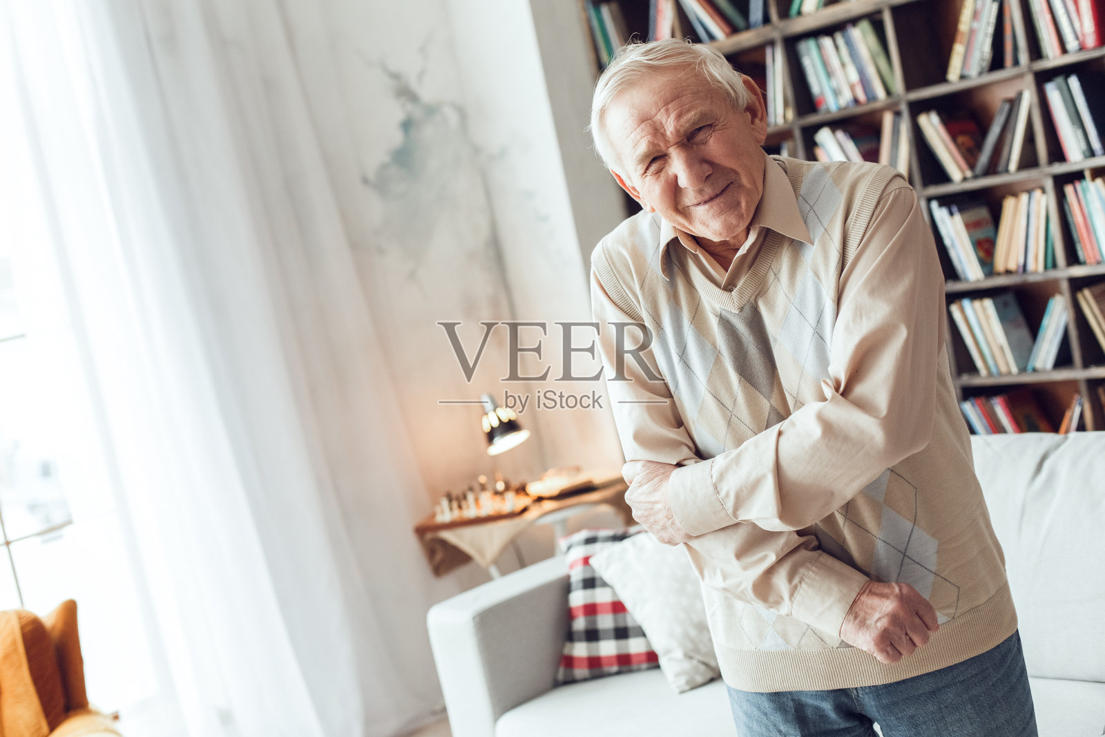 老人独自站在图书馆，手臂酸痛照片摄影图片