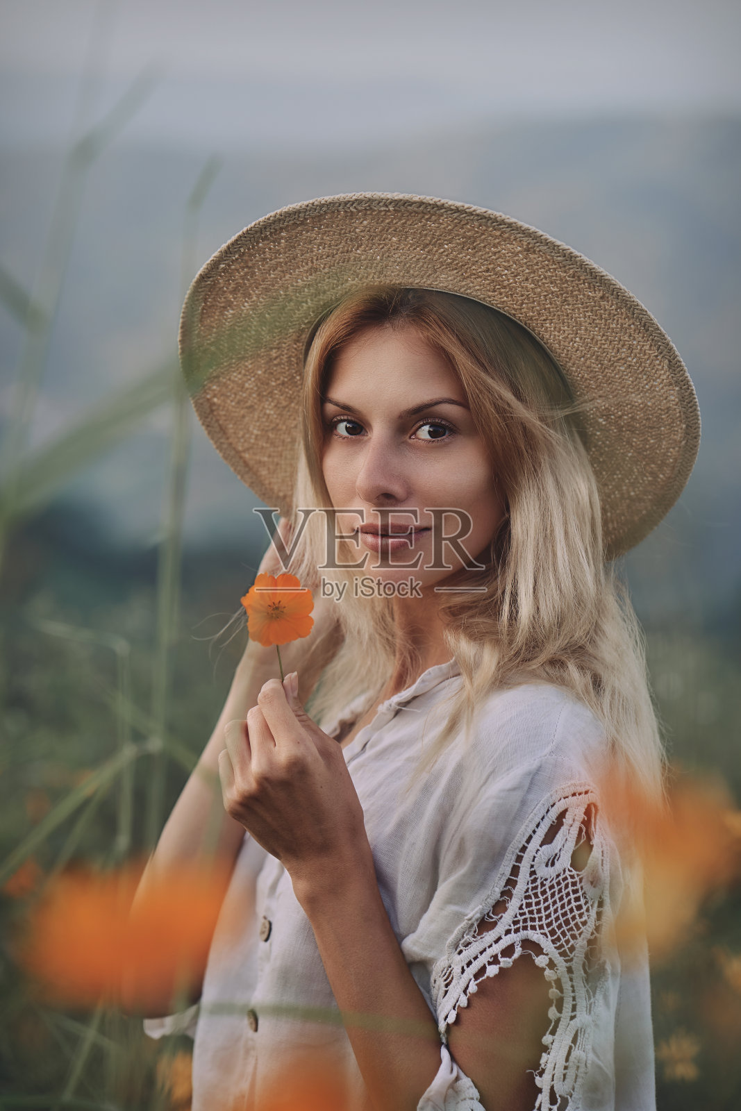 穿亚麻衣服的金发女郎在山上的草地上的香草和野花中漫步照片摄影图片