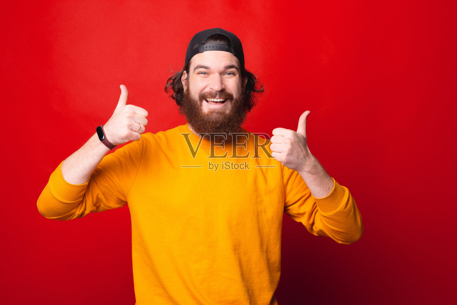 一个兴奋的年轻人举起大拇指，对着镜头微笑照片摄影图片