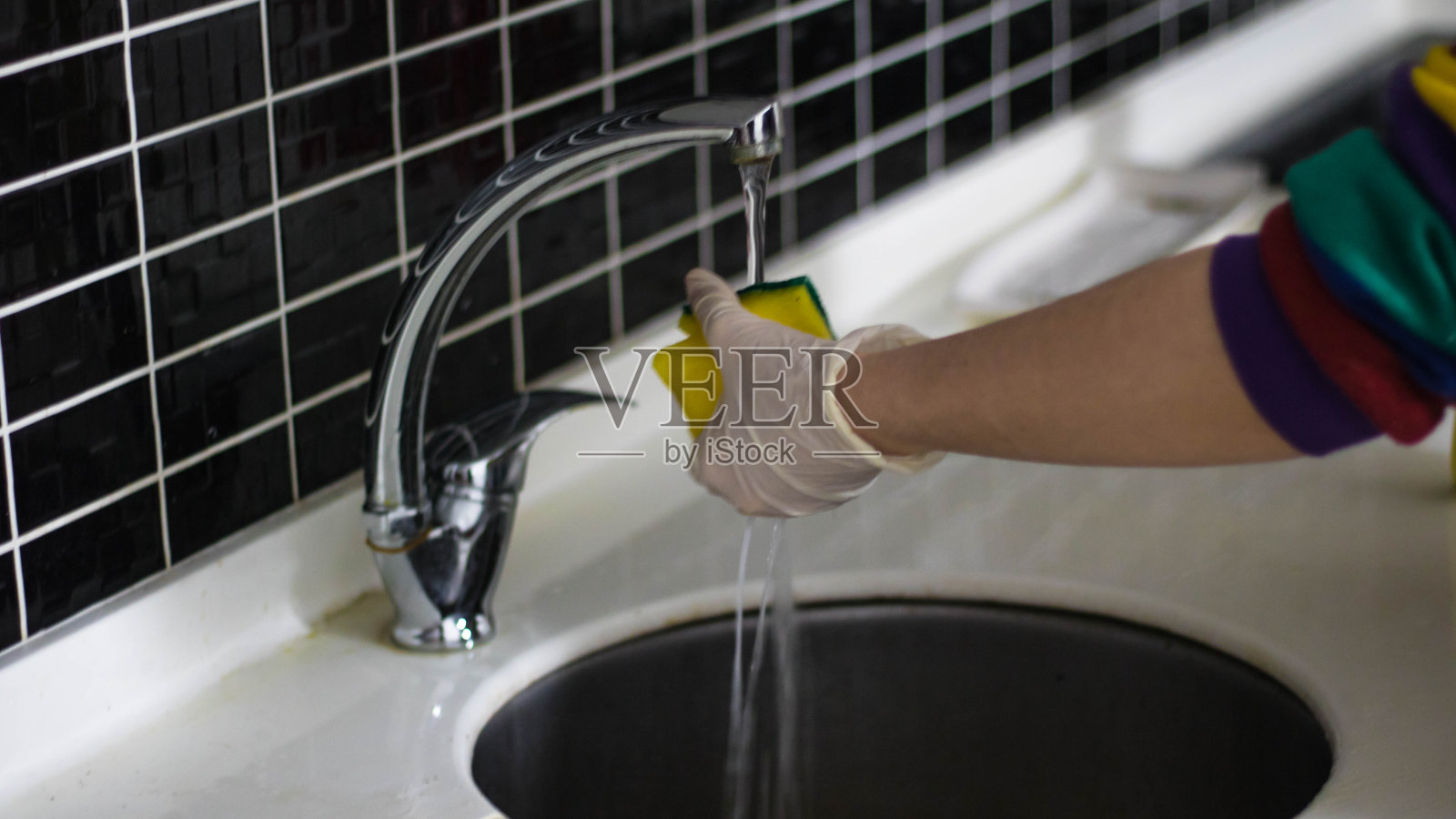 戴着手套用海绵擦拭厨房的人照片摄影图片