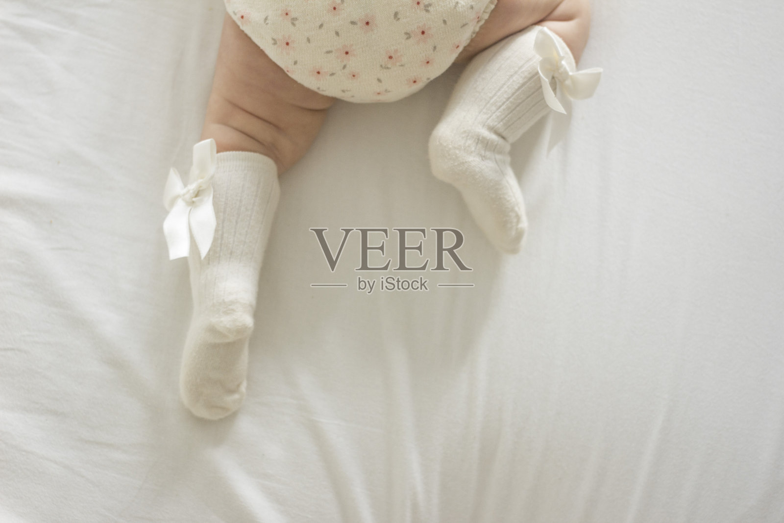 初生女婴的腿，穿着带蝴蝶结的白及膝袜照片摄影图片