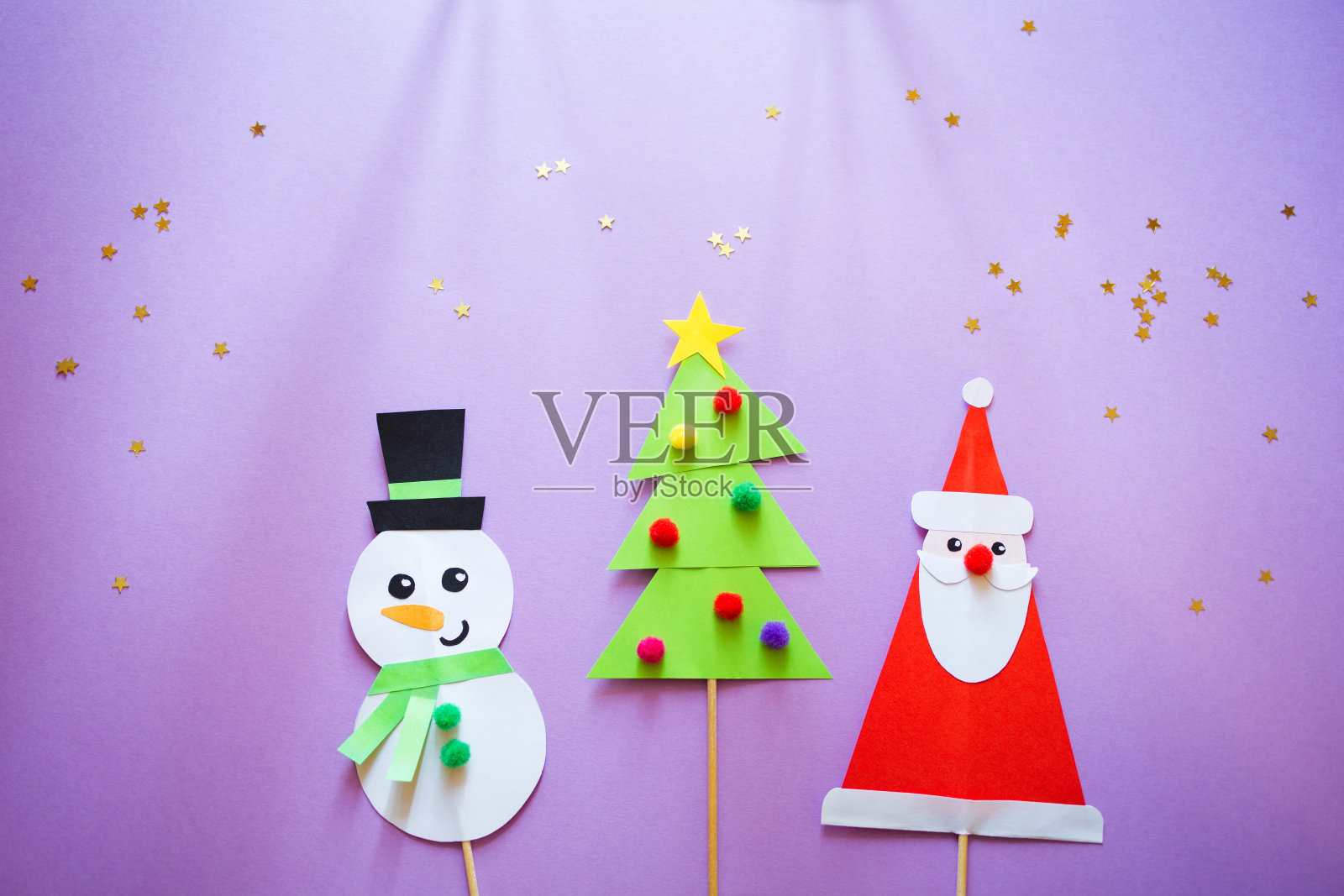 孩子们的纸工艺品。紫色背景上有雪人、圣诞老人和圣诞树。为孩子们创造艺术。新年的概念照片摄影图片