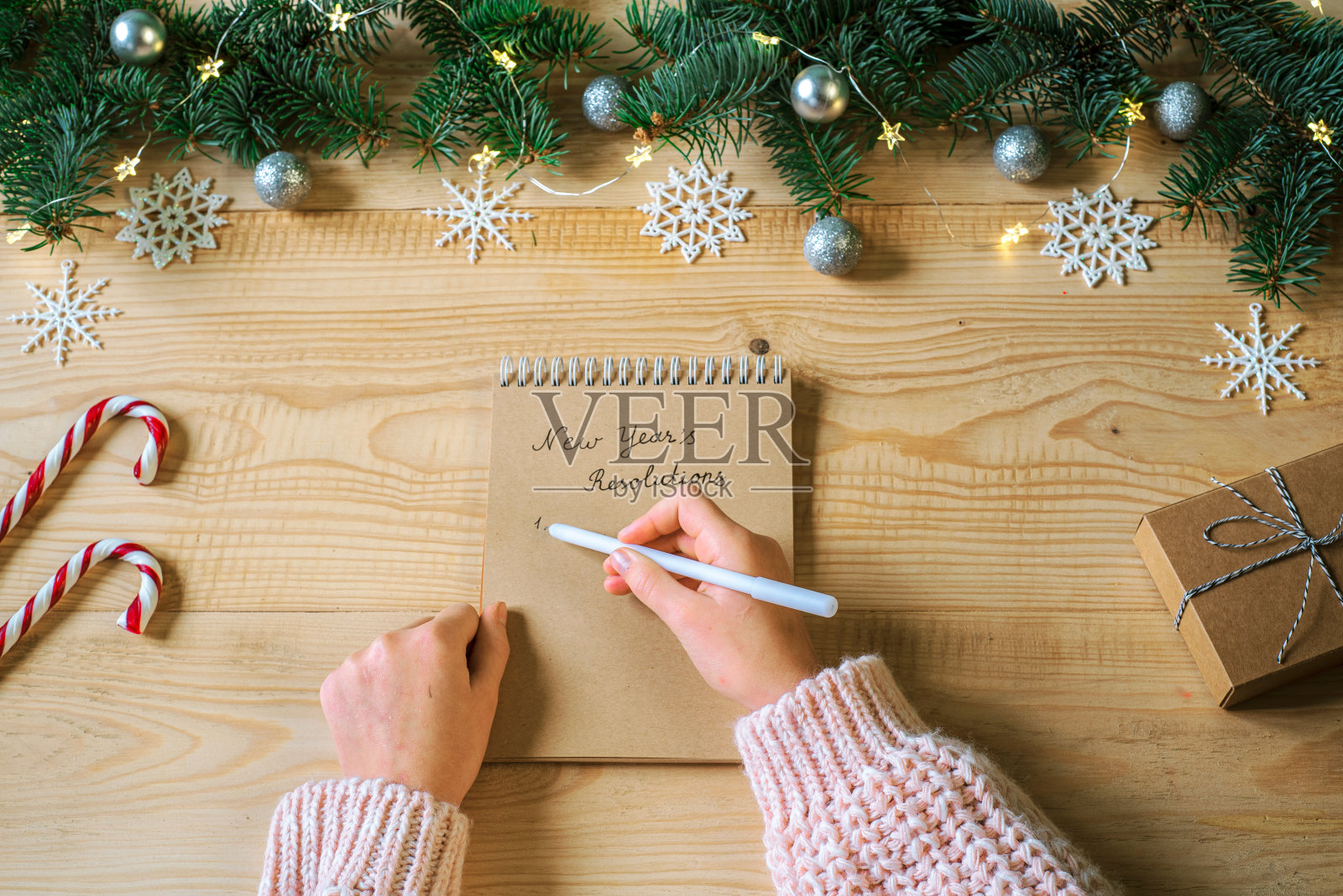在记事本上写下新年决心，背景是圣诞树的树枝和装饰品照片摄影图片