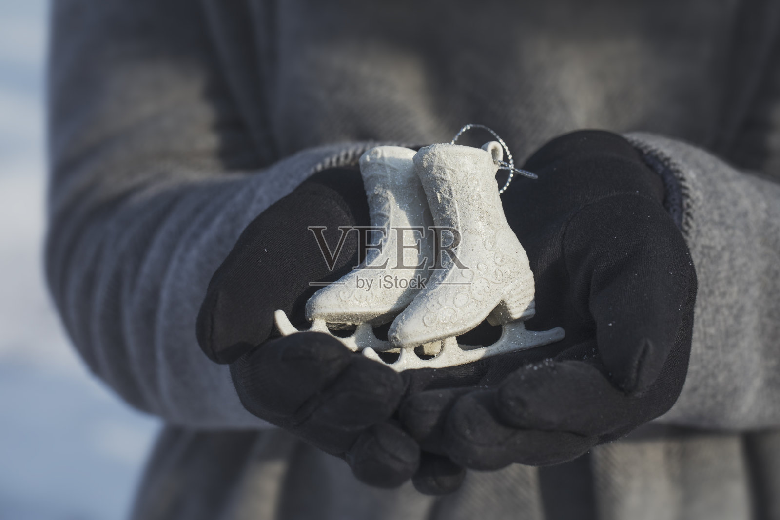 在一个阳光明媚的冬日里，一个戴着手套的女孩手里拿着一个圣诞玩具。照片摄影图片