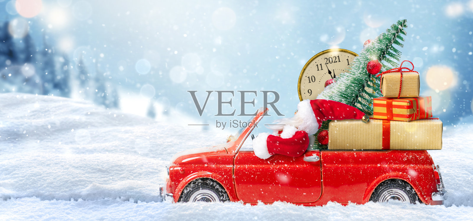 圣诞节即将来临。圣诞老人坐在红色玩具车上为2021年送礼物照片摄影图片