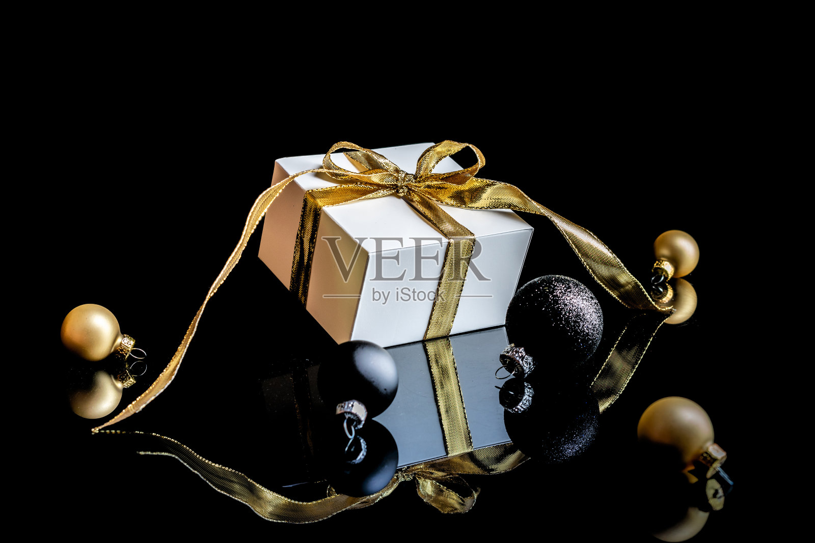 圣诞背景黄金。白色礼盒与金色的丝带，新年球和冬天的树在圣诞节的组成在黑色的背景贺卡。副本的空间。寒假，新年。照片摄影图片