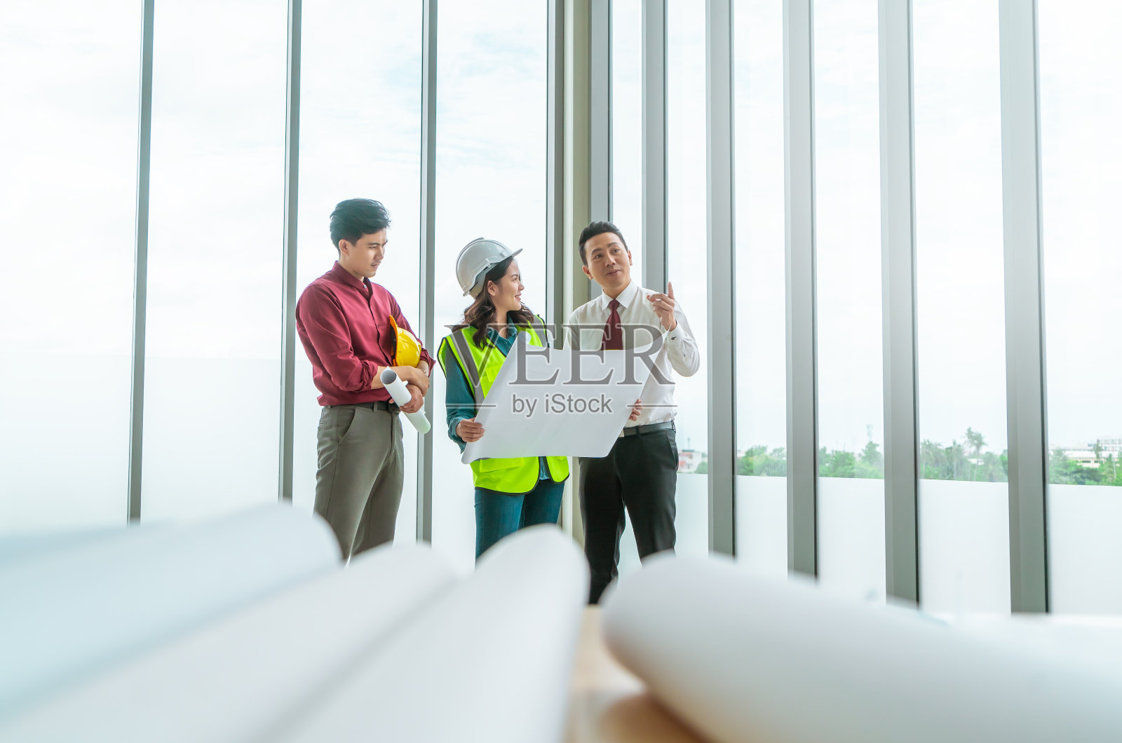 三个施工队正在工地上看建筑和设计。照片摄影图片