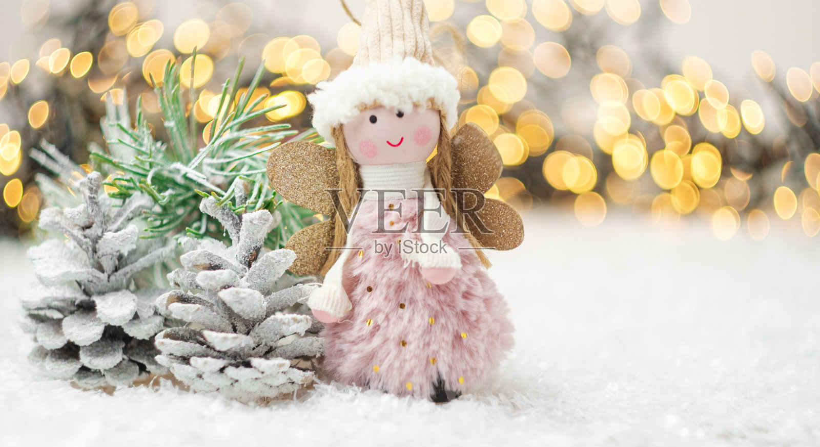 松果，天使，松枝上的雪与金色模糊的灯光背景。冬季装饰用仿空间。照片摄影图片