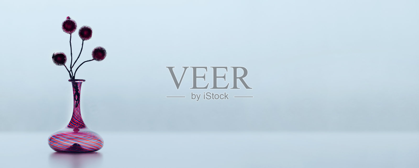 桌上的玻璃花瓶和浆果在冬天的天空背景照片摄影图片