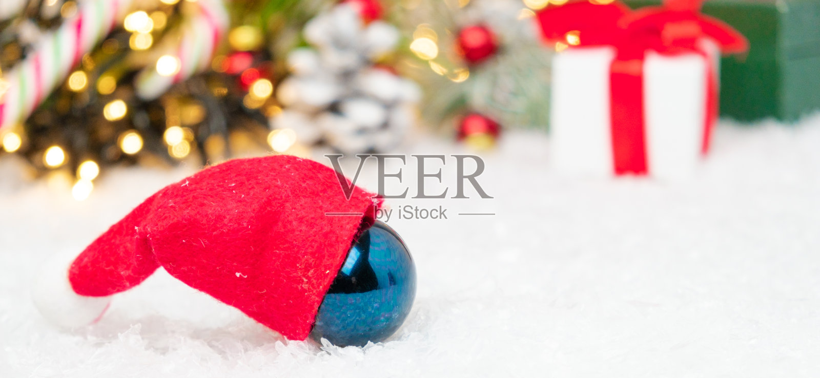 蓝色的圣诞球配红色的圣诞老人帽，上面有圣诞装饰的背景与复制空间照片摄影图片