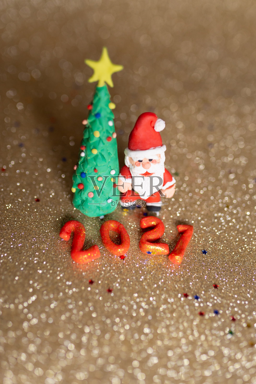 有趣的黏土圣诞概念。彩色手工制作的迷你圣诞树和圣诞老人在金色的背景。2021年新年。照片摄影图片