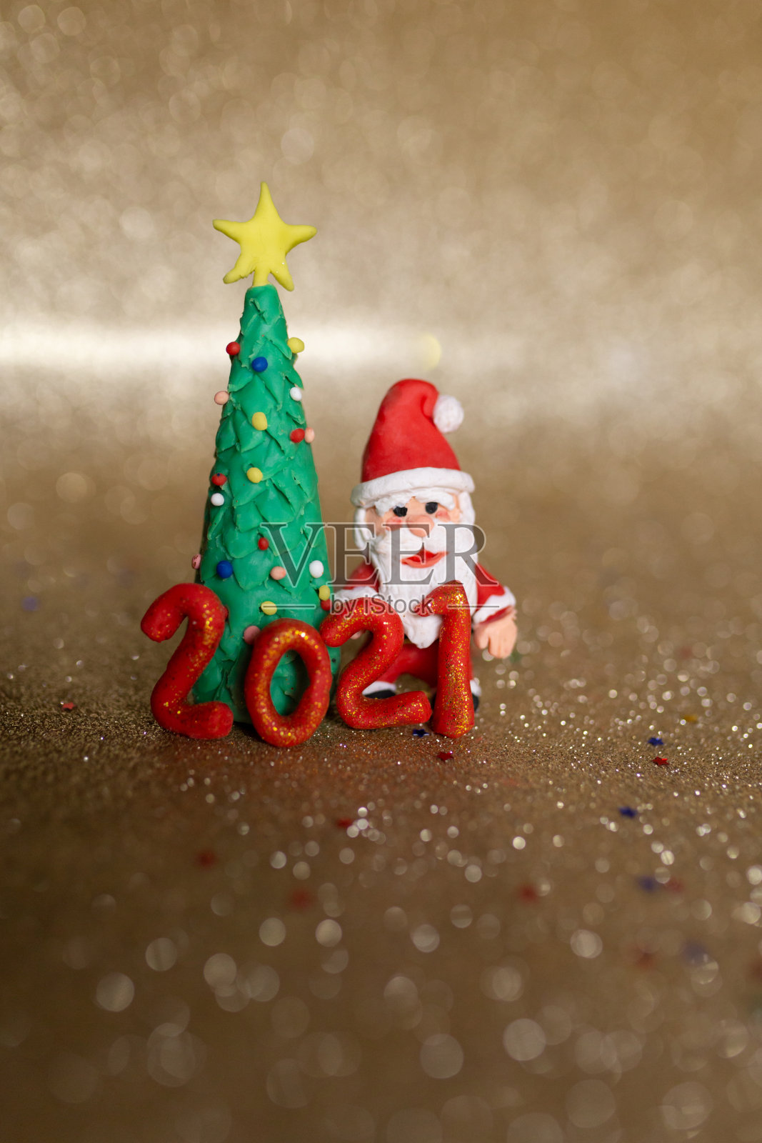 有趣的黏土圣诞概念。彩色手工制作的迷你圣诞树和圣诞老人在金色的背景。2021年新年。照片摄影图片