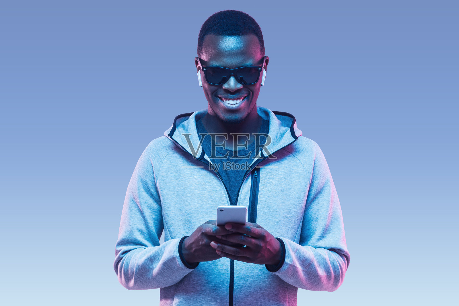 年轻的非洲裔美国人用智能手机和耳机听音乐的肖像照片摄影图片