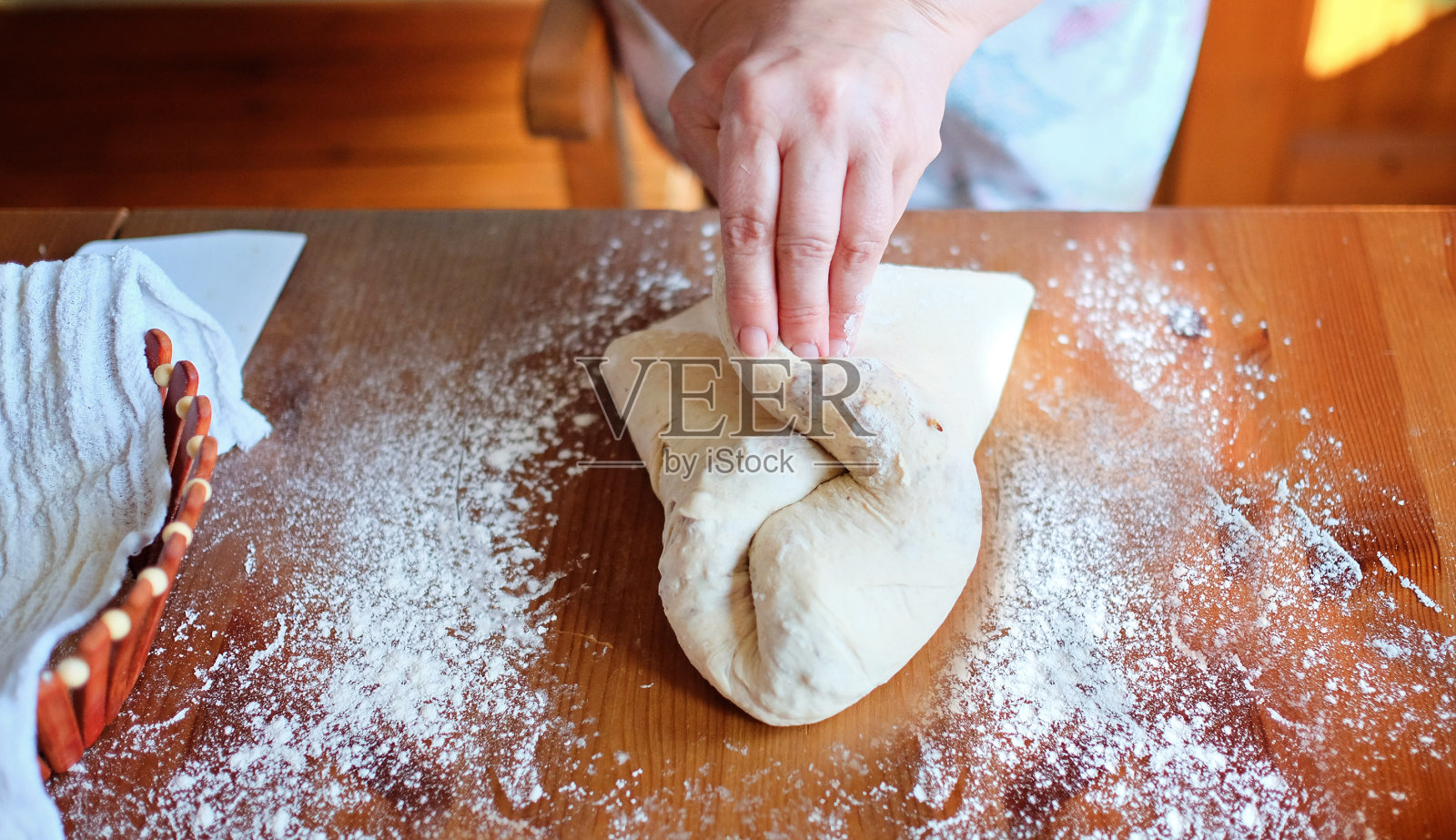 老妇人在自家厨房的桌子上用手揉面团。健康饮食的概念。照片摄影图片