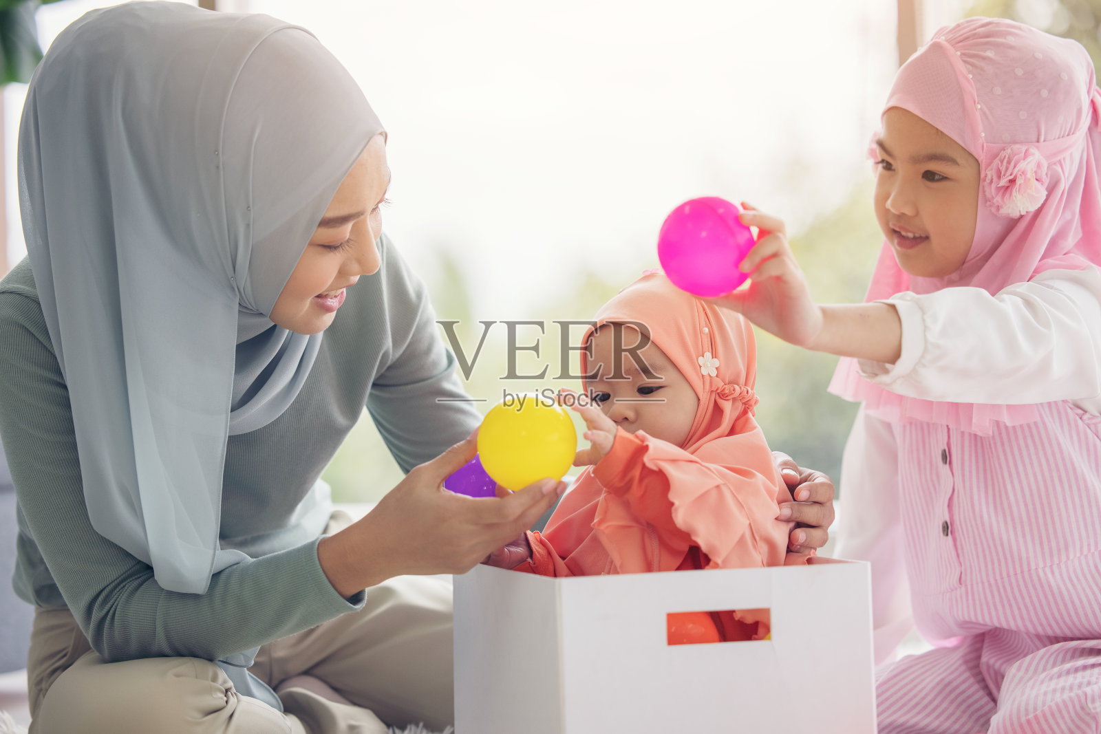 戴着头巾的穆斯林妈妈是她的小女儿坐在客厅里，《爱的关系》照片摄影图片