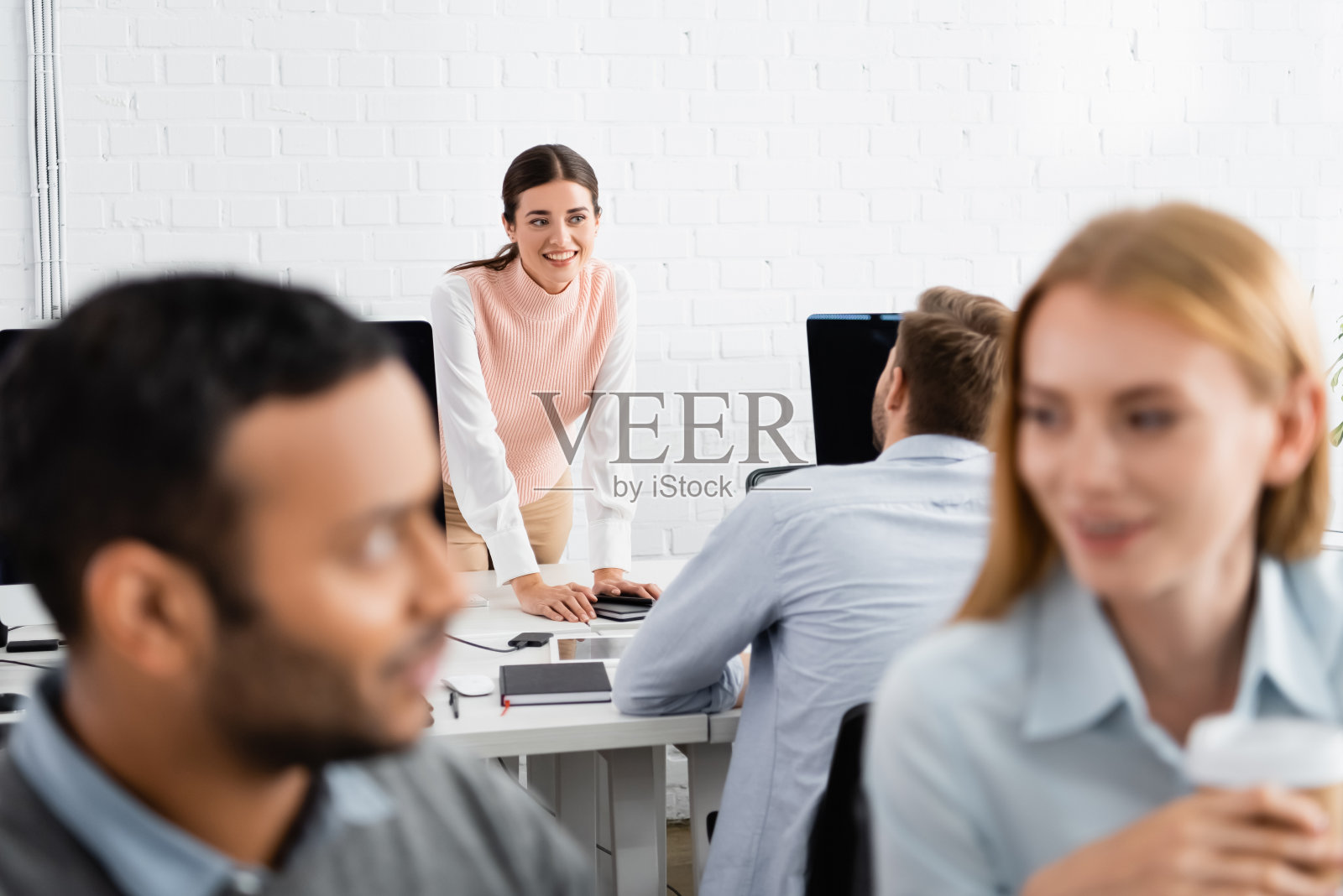 在办公室里看着设备旁的同事的女商人照片摄影图片