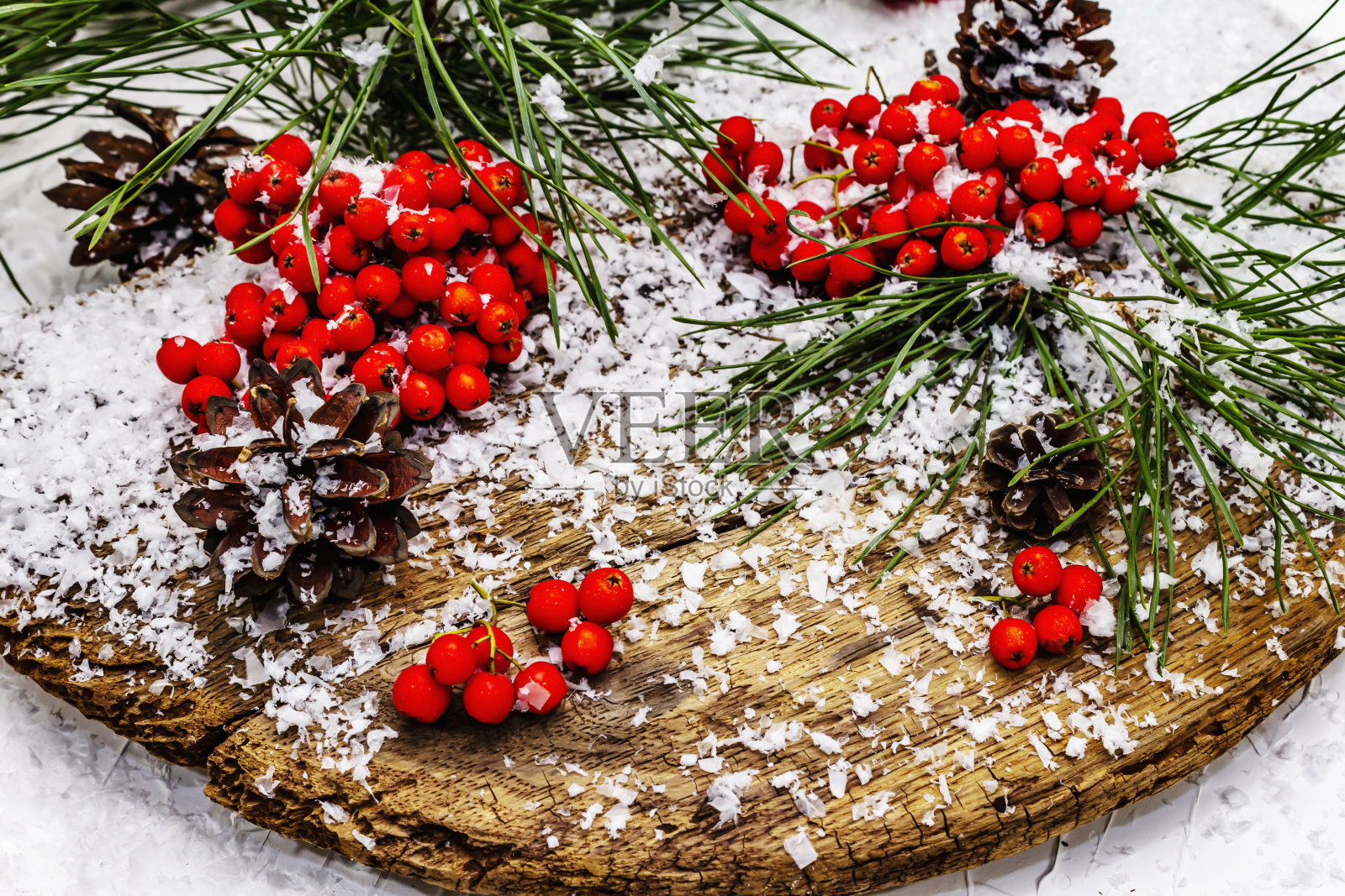 在一张被雪覆盖的旧桌子上，松树突起和树枝上长着红色花楸照片摄影图片