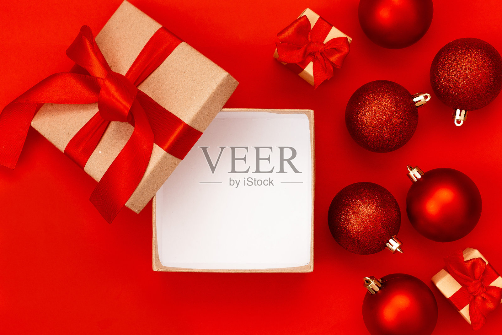 打开礼盒，红色圣诞球在红色背景与复制空间。圣诞组成。平躺，俯视图。简约的风格。照片摄影图片