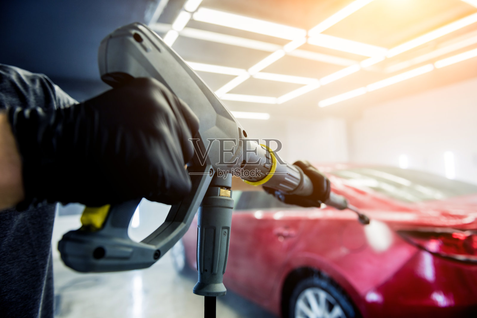 工人在洗车厂用高压水洗车。照片摄影图片