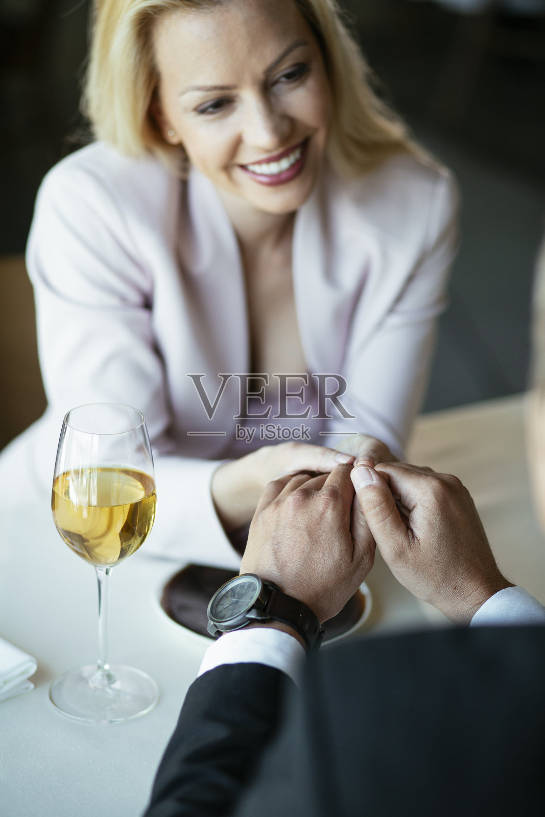 幸福的女人喝着酒，在餐厅里牵着手。照片摄影图片