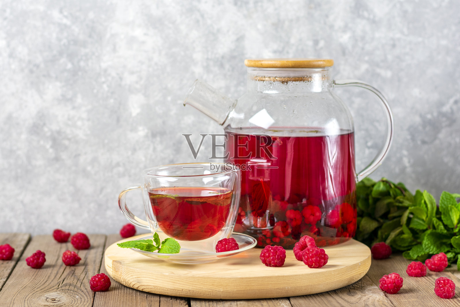 草药茶，用浆果，覆盆子，薄荷叶和木槿花玻璃茶壶和杯子放在木桌上照片摄影图片