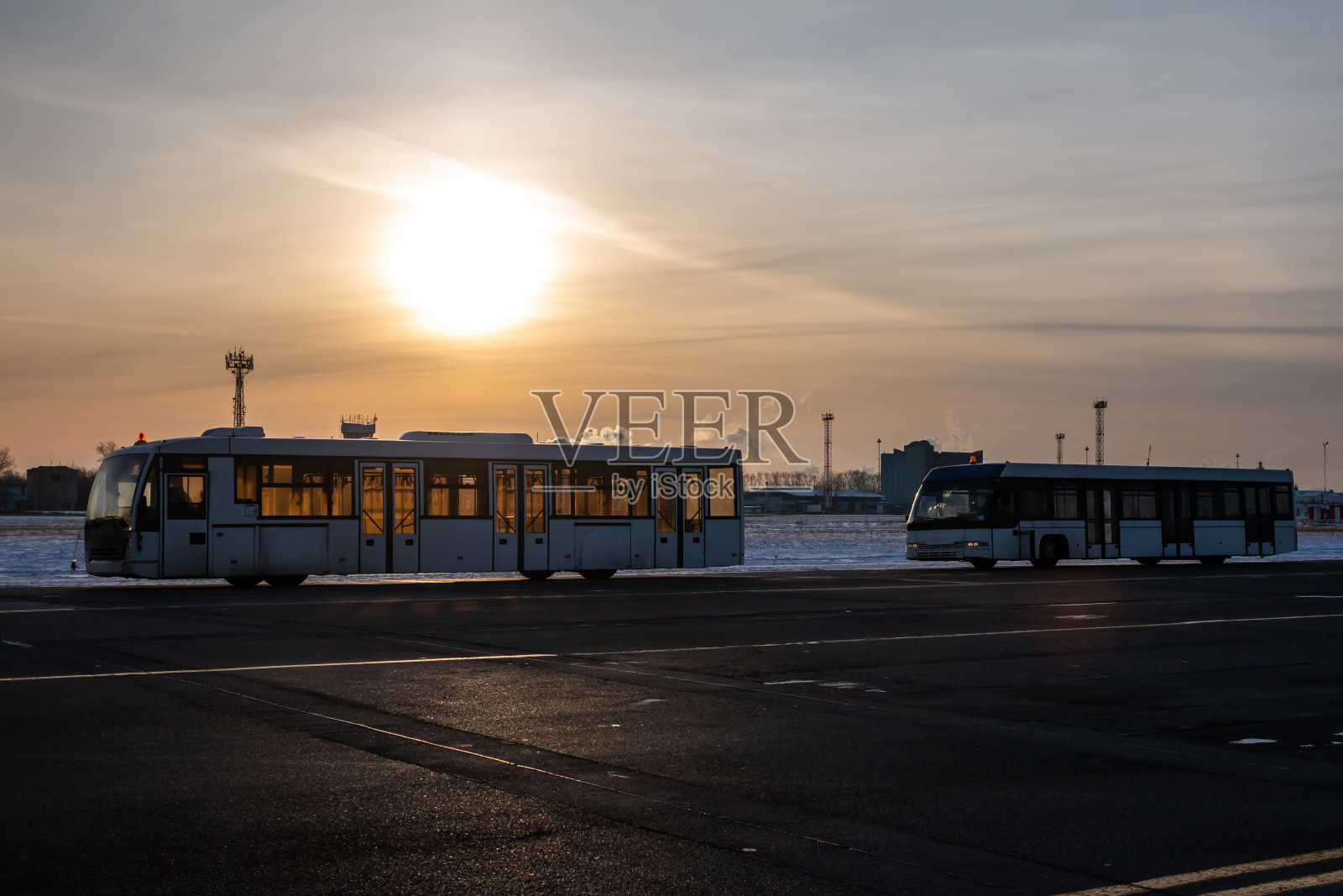 在一个寒冷的冬天的晚上，两辆空无一人的机场班车照片摄影图片