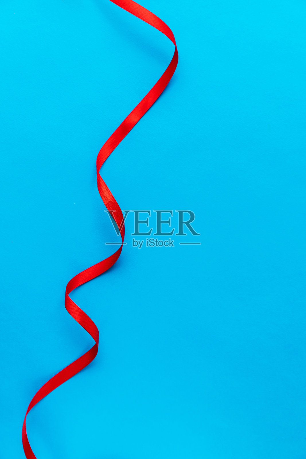蓝色背景上垂直的波浪红丝带。Copyspace。副本的空间。明信片。背景文本。电脑的壁纸。照片摄影图片