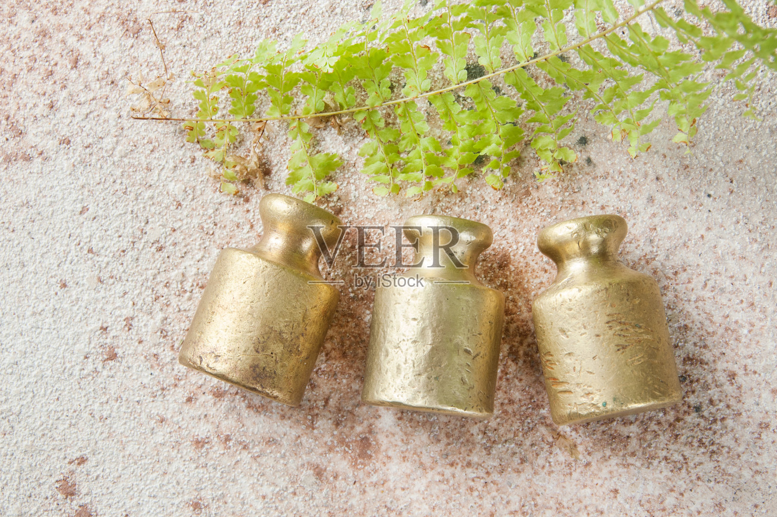 三个古铜色砝码用于混凝土背景下的秤。照片摄影图片