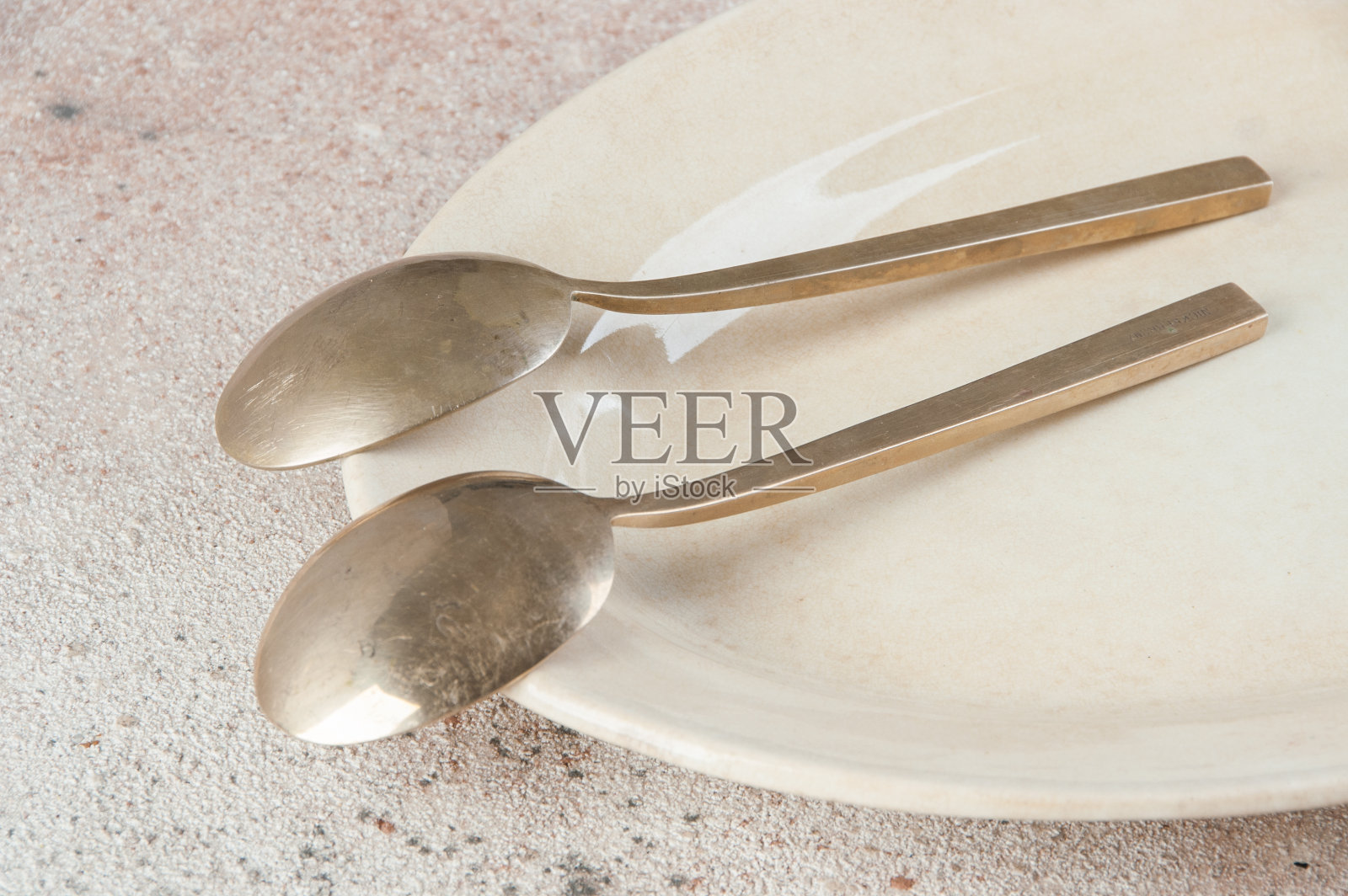混凝土背景上有两个古老的青铜勺子。照片摄影图片