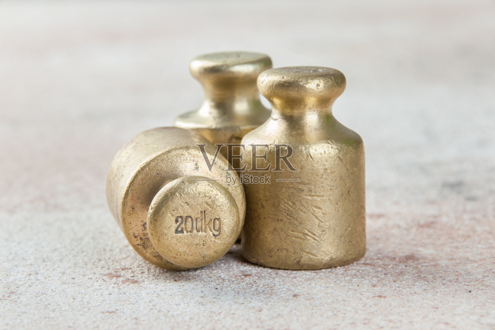 三个古铜色砝码用于混凝土背景下的秤。照片摄影图片