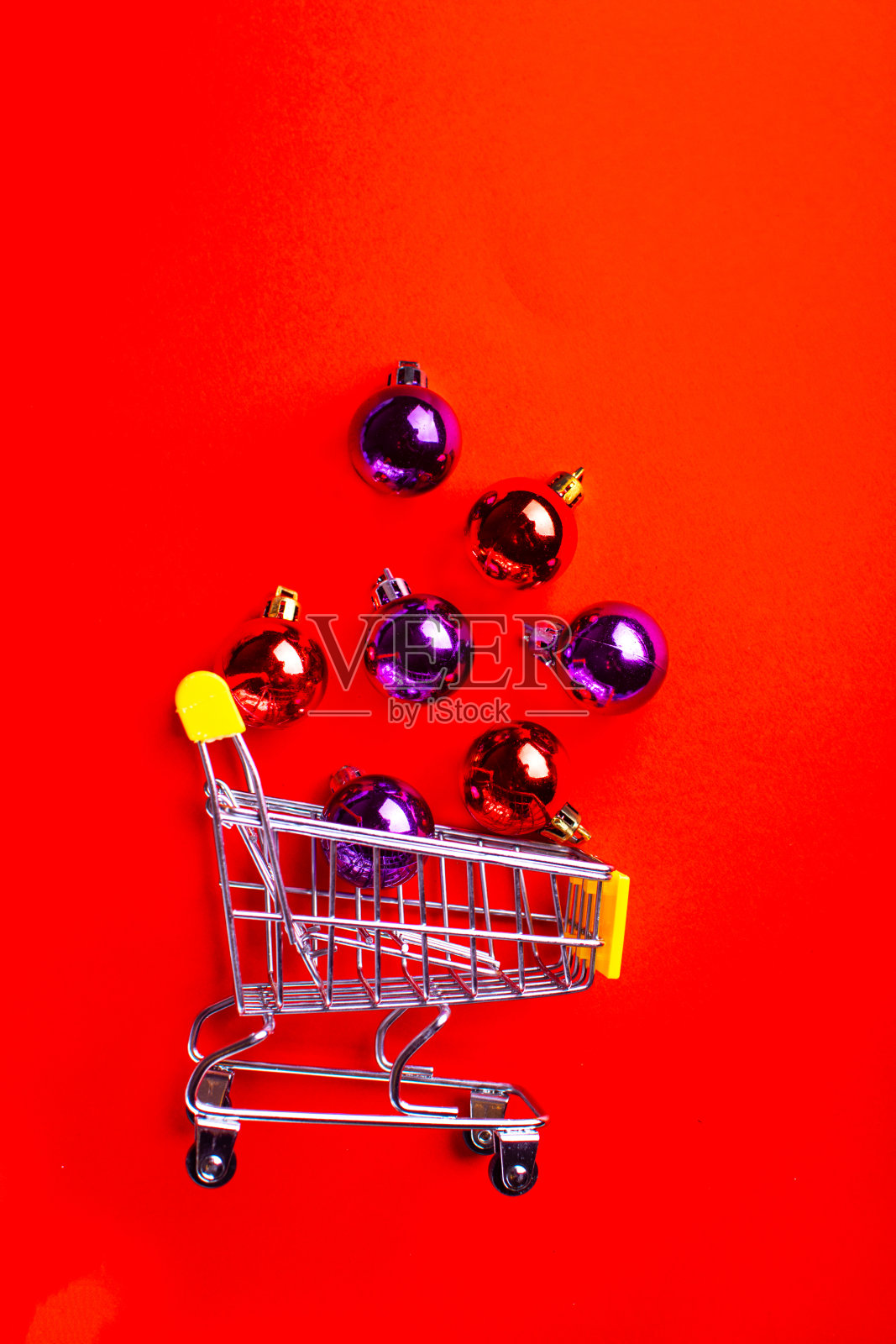 购物车里装满了红色背景的圣诞球。照片摄影图片