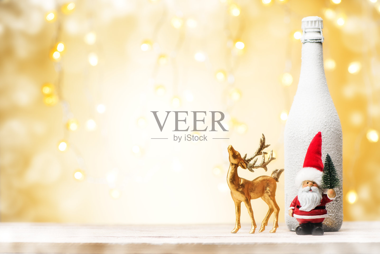 圣诞节和新年假期的背景。圣诞老人与金鹿和瓶香槟的节日背景与散景和花环灯和复制空间。照片摄影图片
