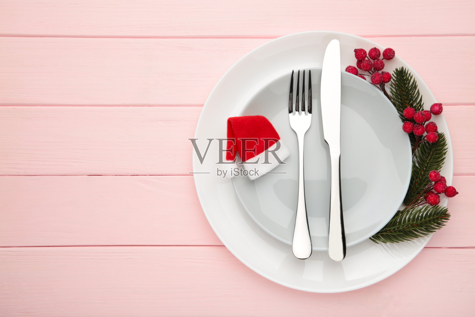 圣诞餐桌的地方设置与红色装饰在粉红色。节日的背景照片摄影图片