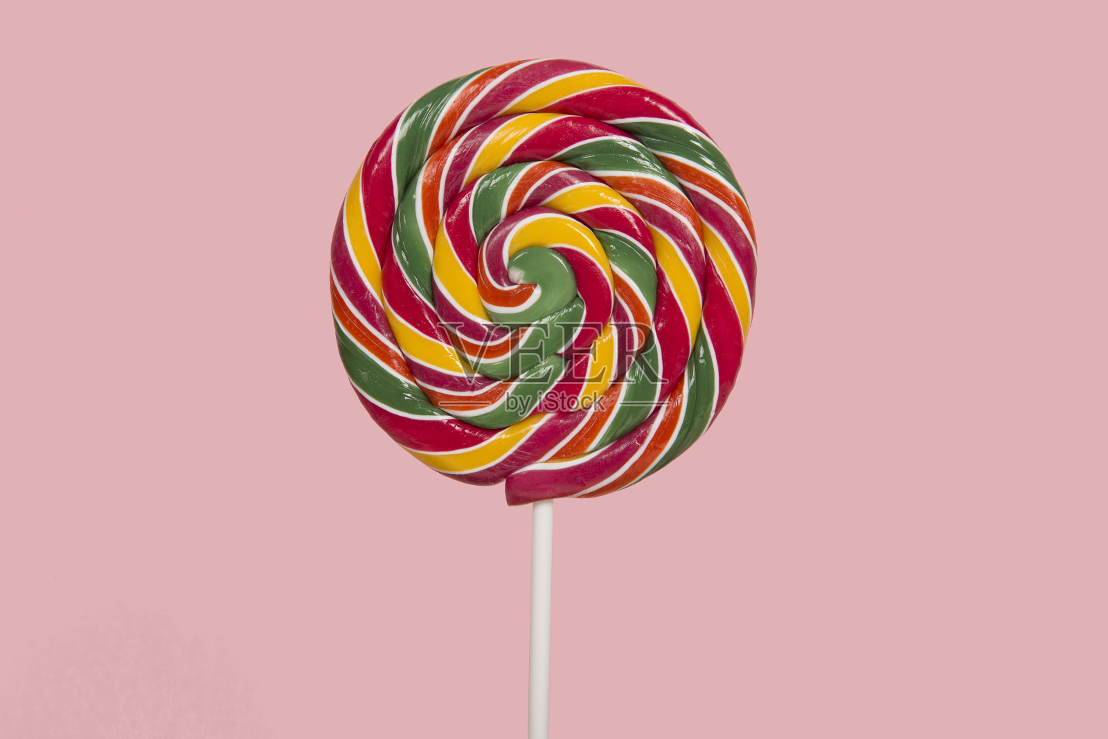 粉红色背景上的圆形彩色棒棒糖照片摄影图片