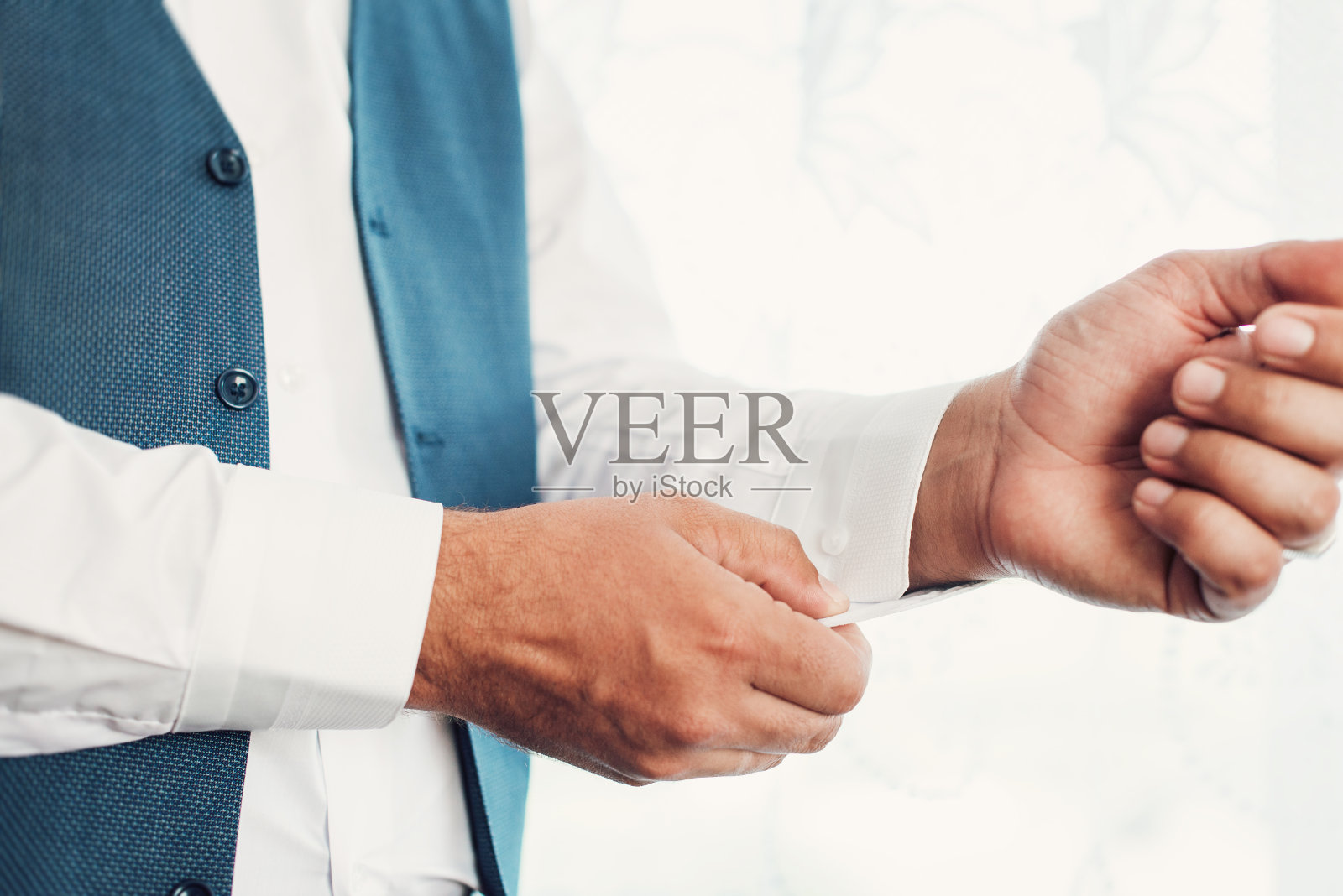 那个男人系好衬衫上的扣子。早上好，新郎。新郎的手在扣白衬衫。照片摄影图片