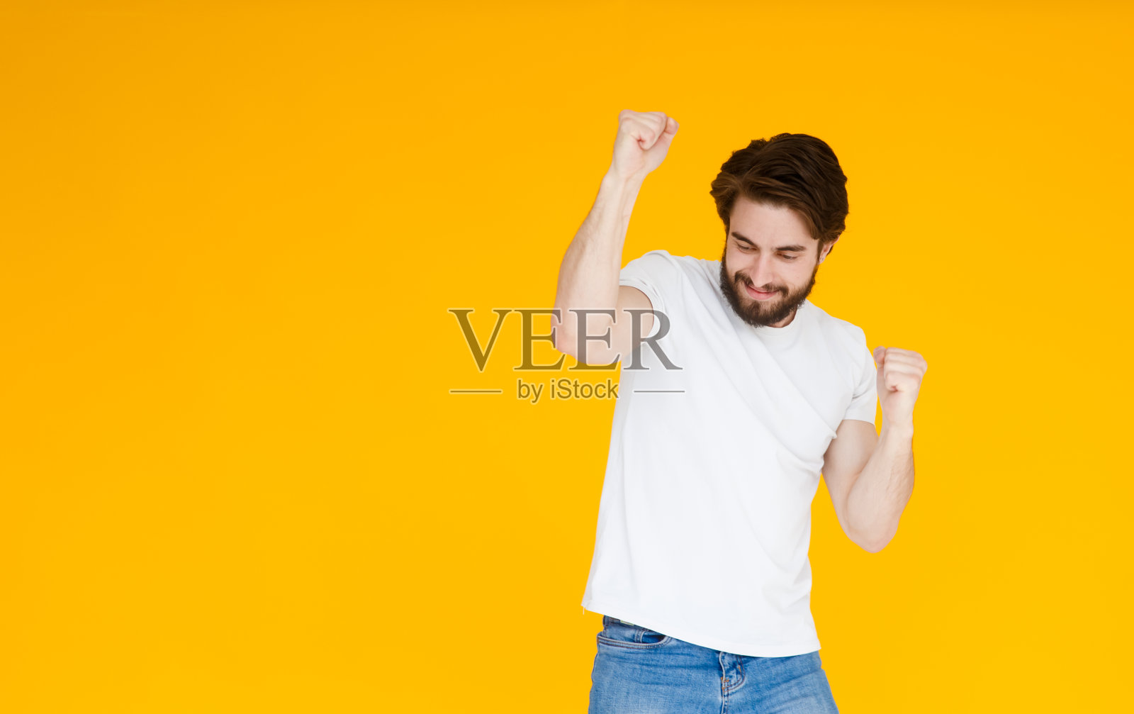笑年轻的胡子男子摆出孤立的黄色背景的工作室肖像。人的情感生活理念。模拟拷贝空间。踮起脚尖，摊开双手照片摄影图片
