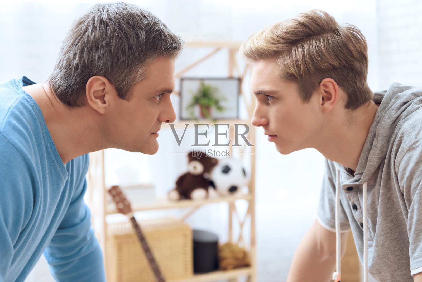 父亲和儿子面对面站着。父亲和问题少年互相恐吓。照片摄影图片