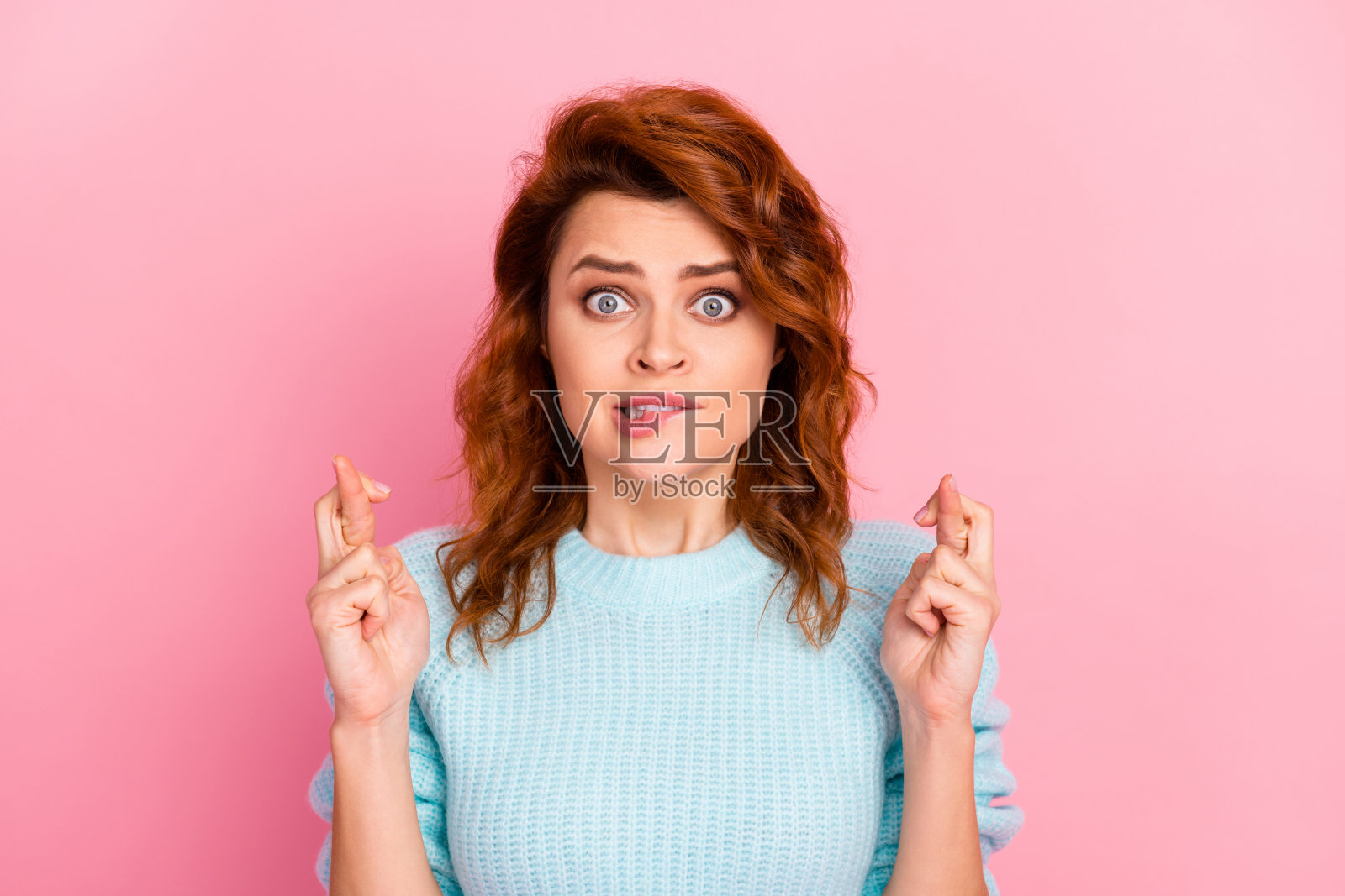 她的特写肖像，她漂亮迷人，可爱，可爱可爱，害怕的卷发女孩担心咬嘴唇，显示交叉的手指孤立的粉红色柔和的颜色背景照片摄影图片