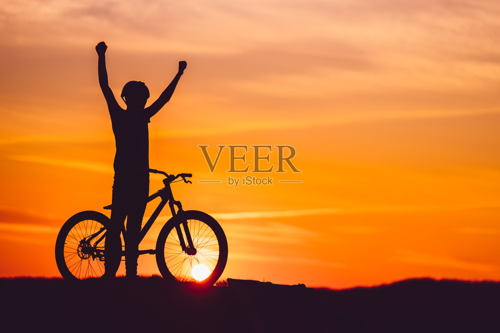 日落时一个山地车手举起的剪影照片摄影图片