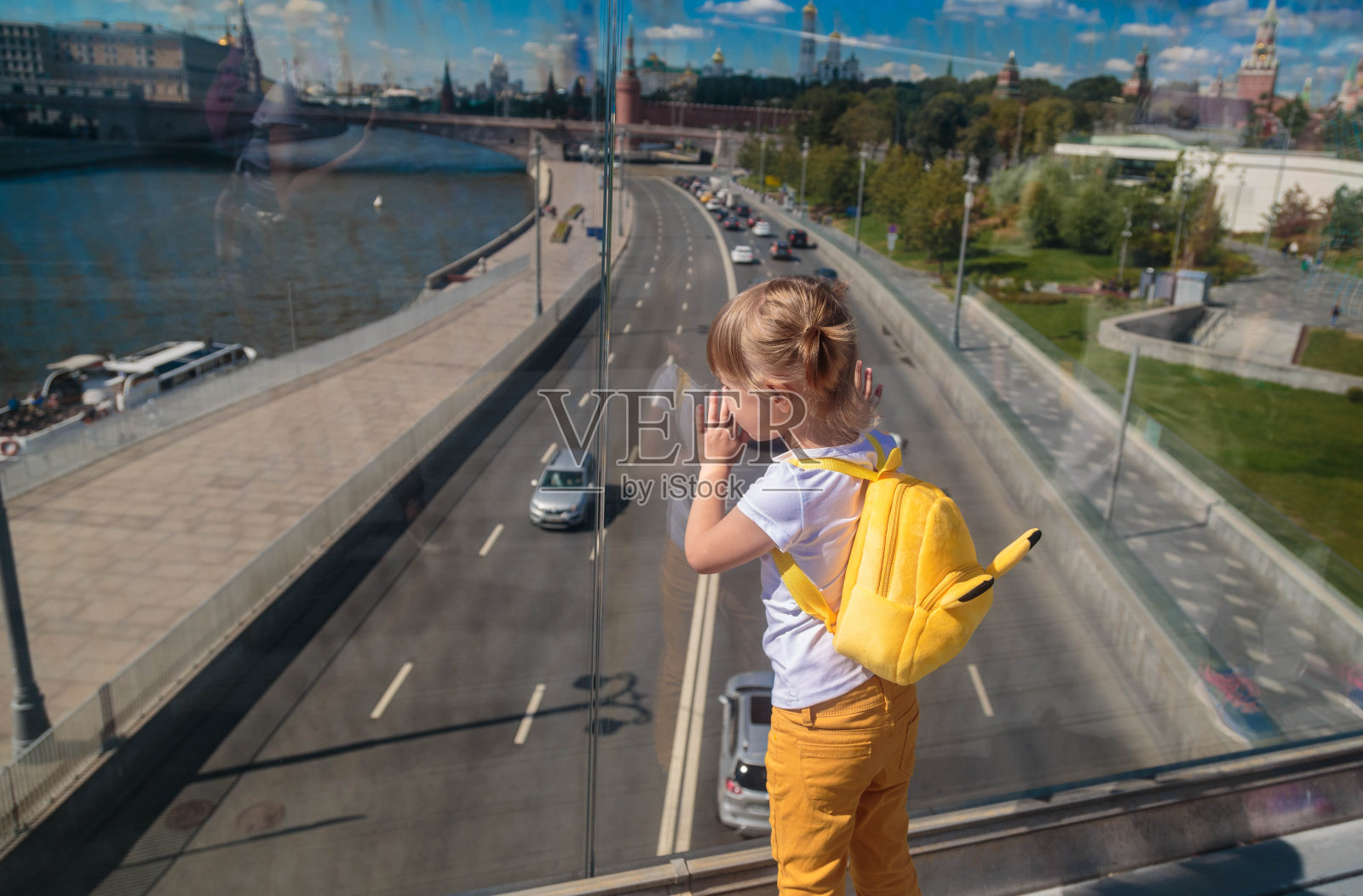 在莫斯科的一座浮桥上，一个小女孩透过玻璃看着。照片摄影图片
