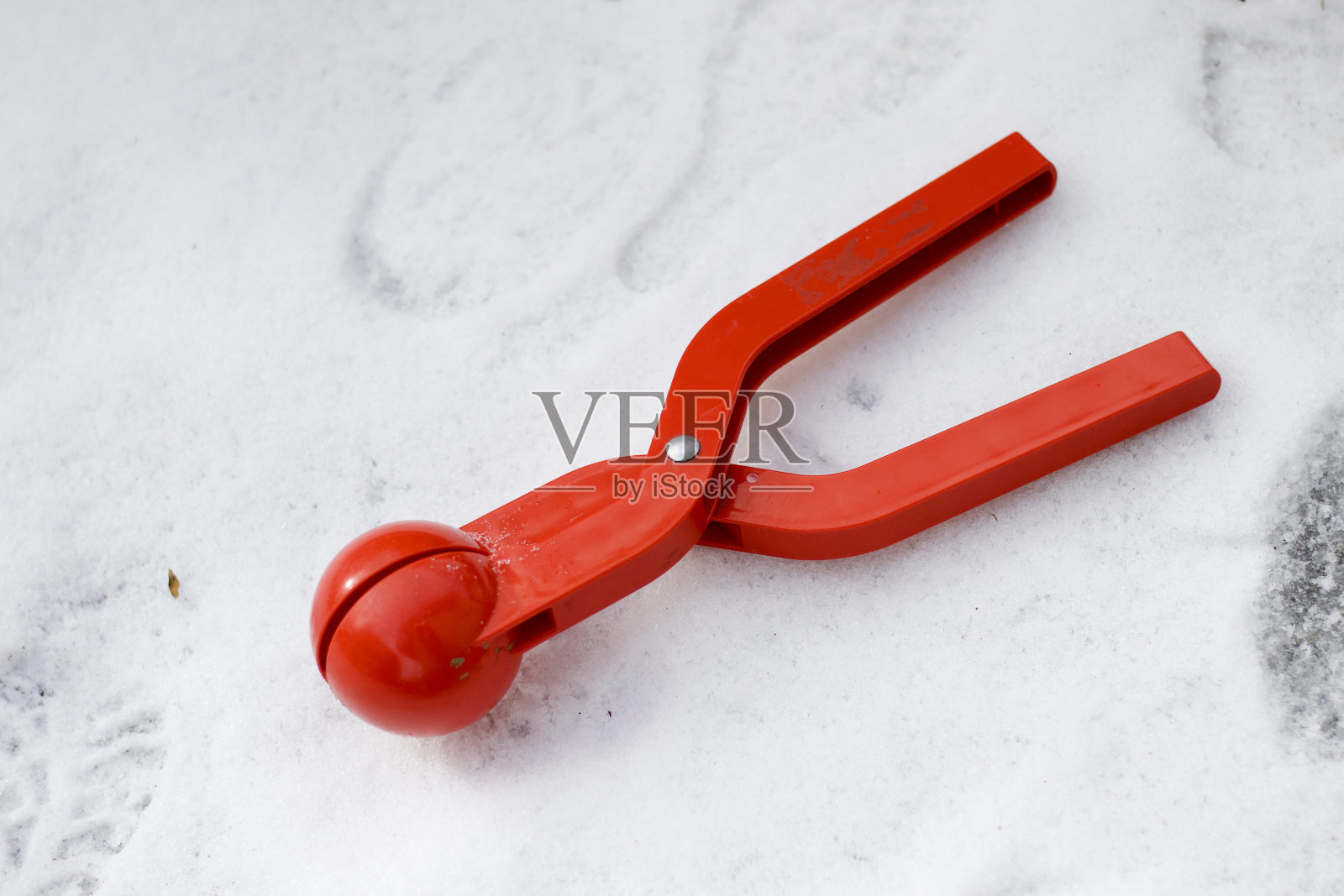 亮红色的塑料装置，玩具夹，用于在白色的雪地背景上制作雪球。快乐的童年和冬季有趣的游戏概念。照片摄影图片