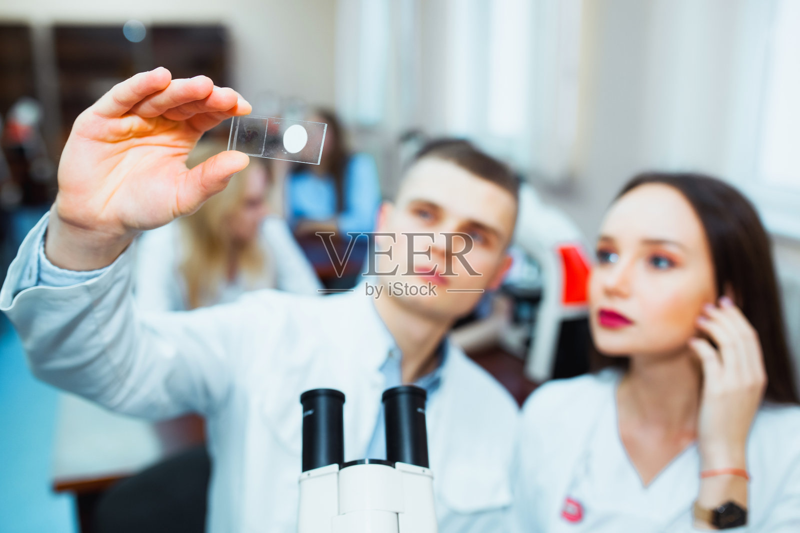 在生物课上透过显微镜看的高中生。年轻的科学家正在做一些研究照片摄影图片