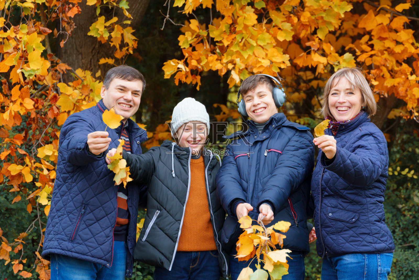 一家人在秋城公园户外休闲，快乐的人们聚在一起，父母和孩子们，他们谈笑风生，在黄色的枫叶旁摆姿势，美丽的大自然照片摄影图片