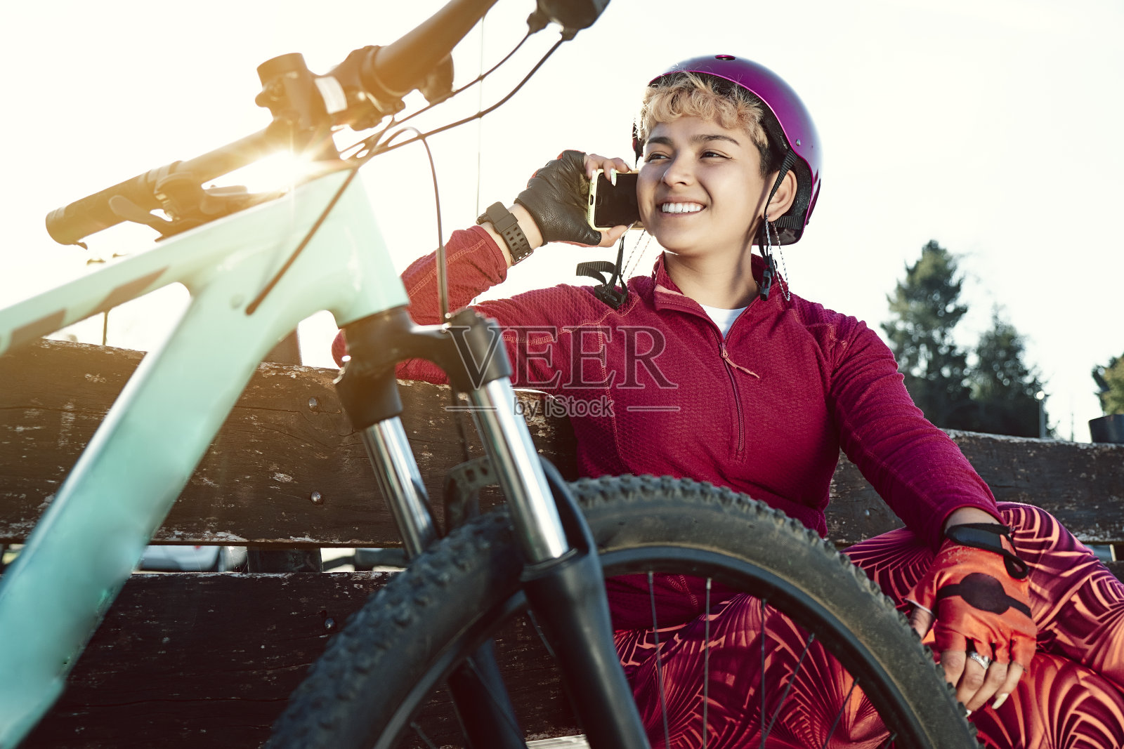 年轻的女运动员用手机骑自行车。照片摄影图片