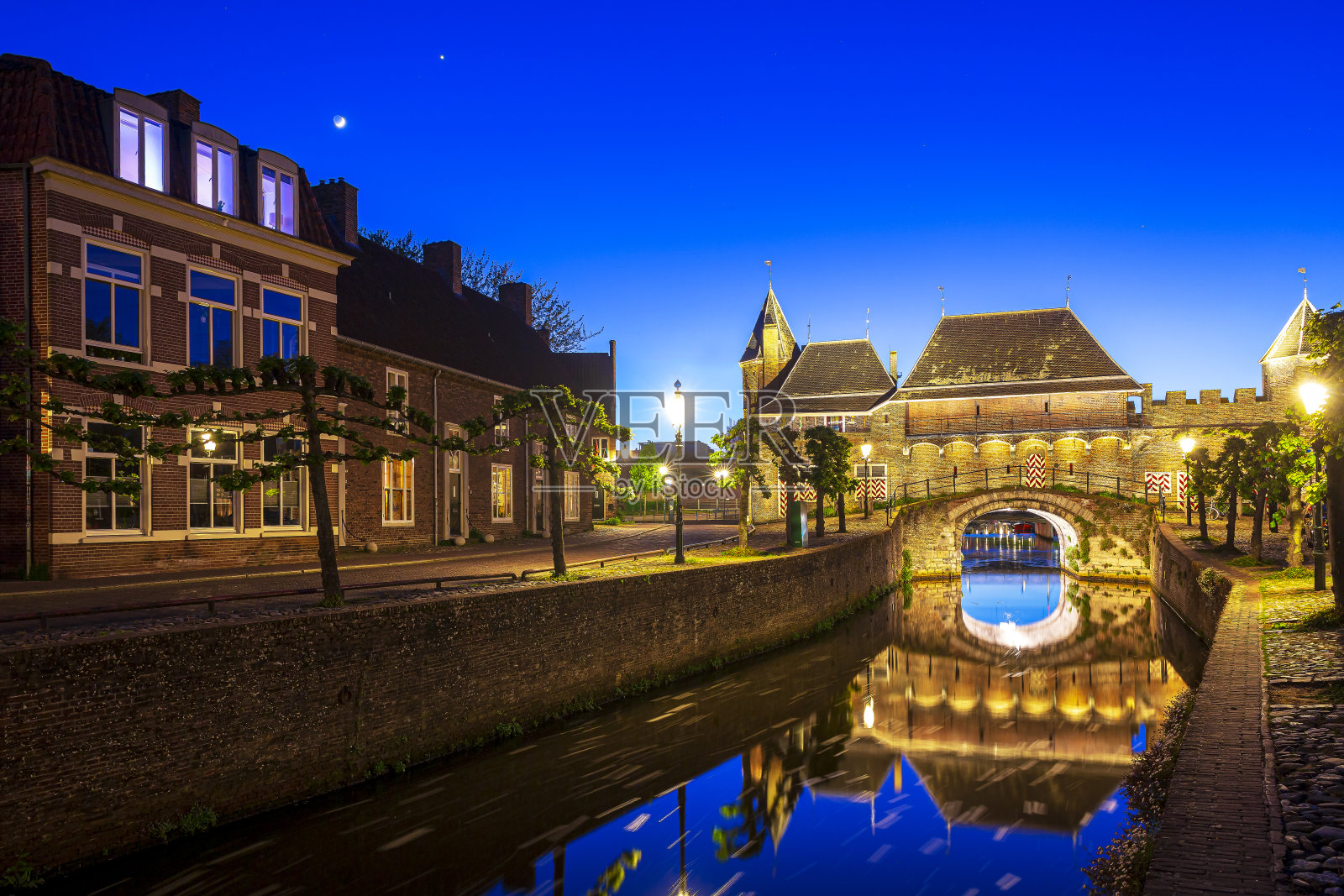 日落时分，荷兰阿默斯福特市的老城门Koppelpoort。两座塔与一个拱门相连。照片摄影图片