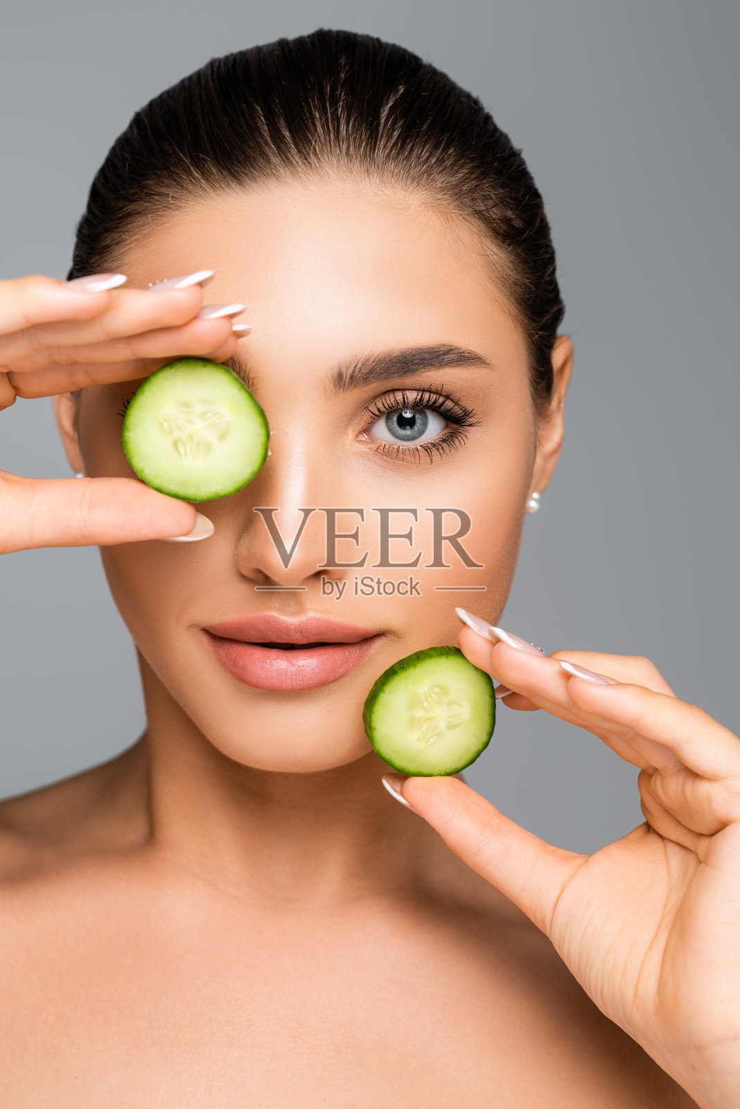 女人赤裸的肩膀和黄瓜孤立在灰色照片摄影图片