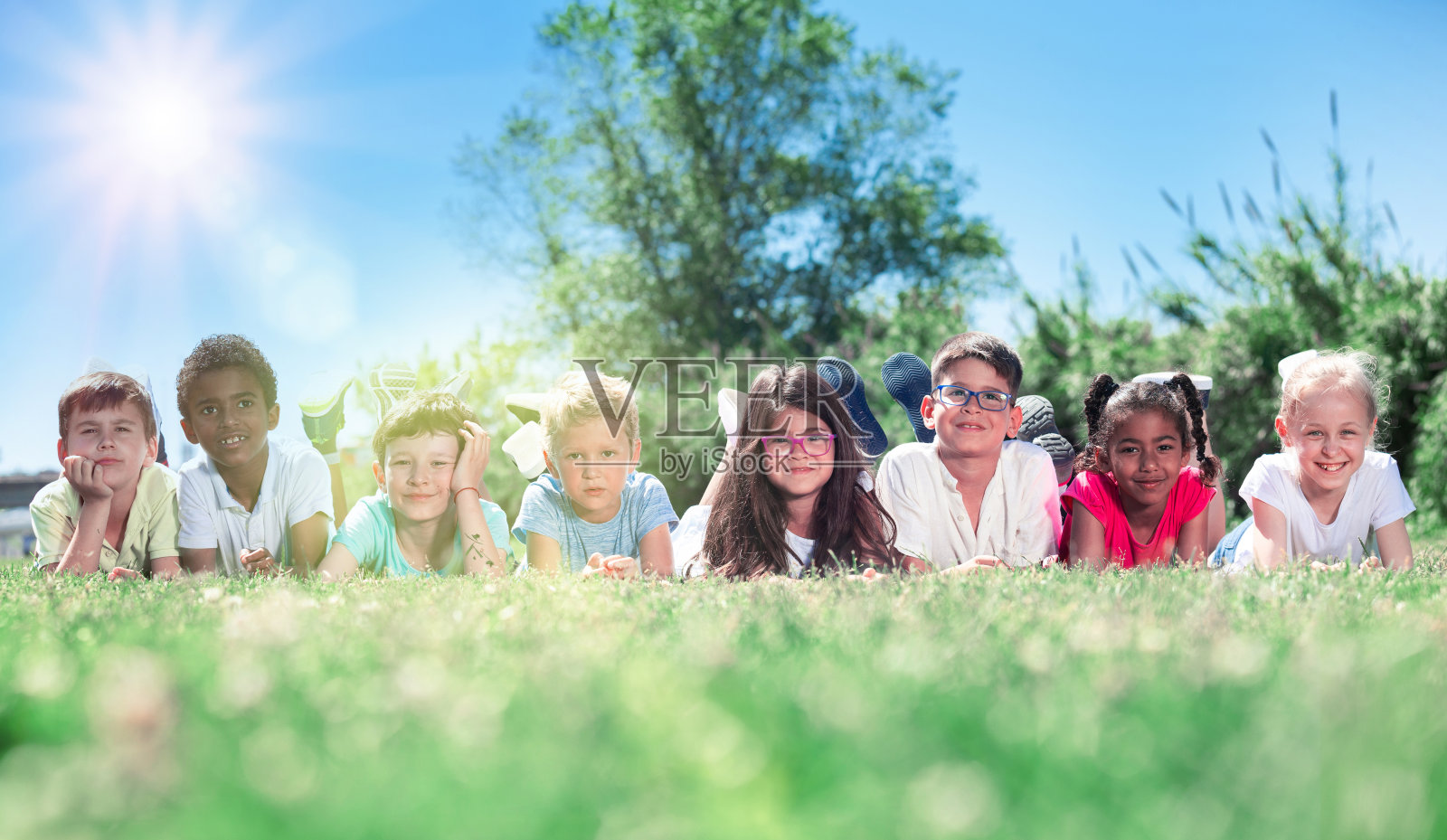 在一个阳光明媚的日子里，快乐的孩子们躺在绿色的草地上照片摄影图片
