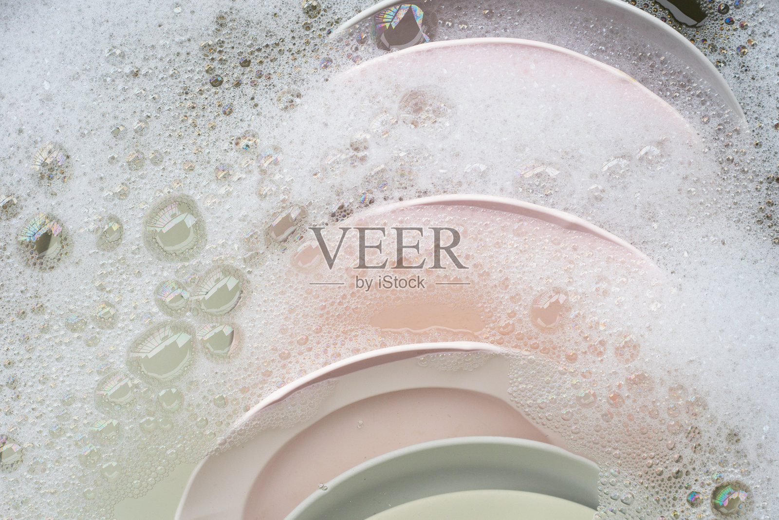 洗盘子，靠近浸泡在厨房水槽中的器具。照片摄影图片